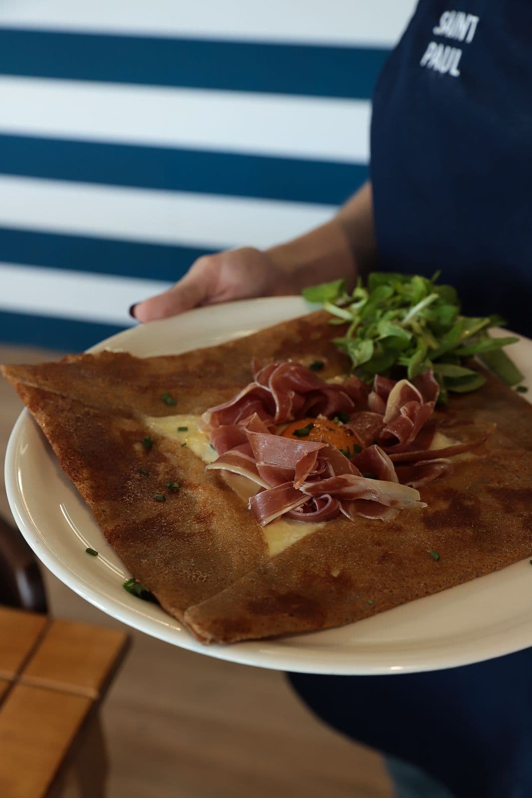 Pohánková galette s prosciuttom, vajcom a šalátom, podávaná pri pulte Saint Paul
