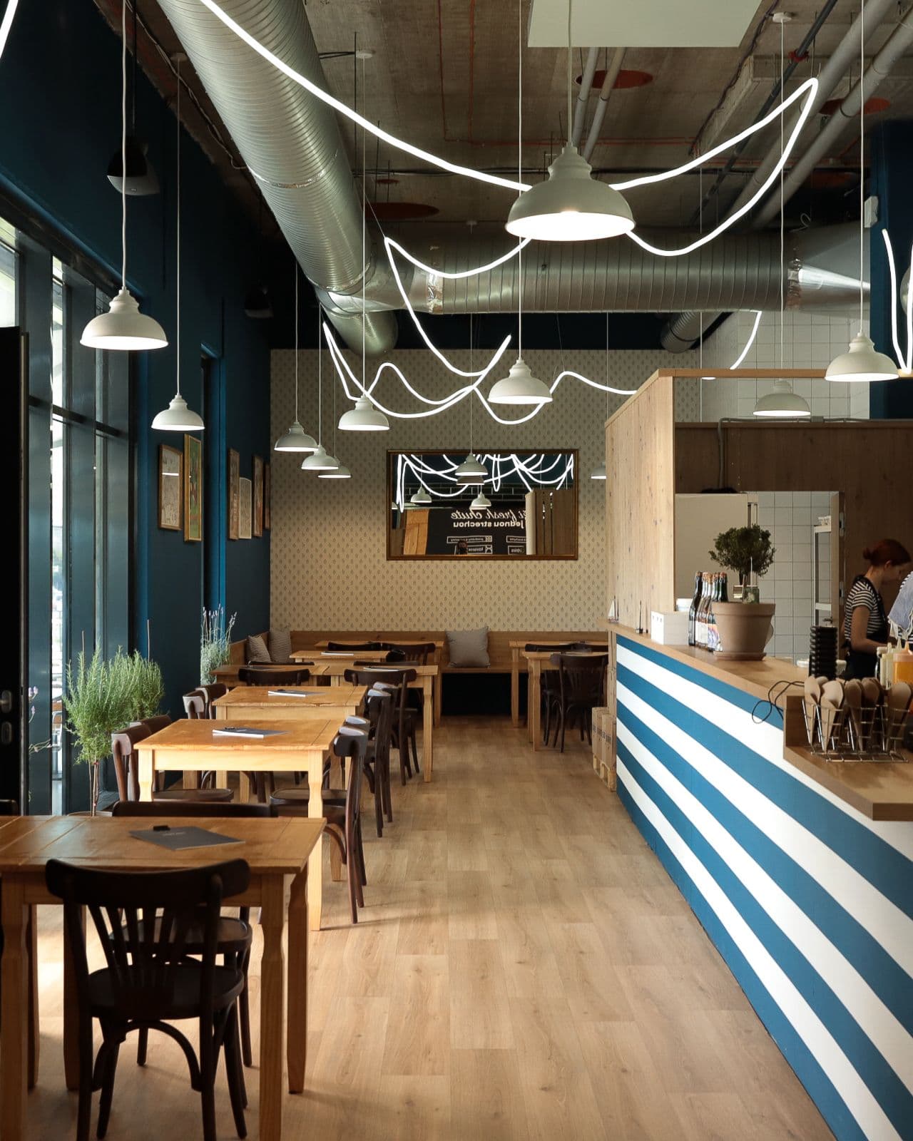 Interiér Saint Paul vo Fresh Markete — drevené stoly, veľké okná a modro-biely pult